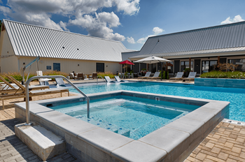 a swimming pool with chairs and a building in the background